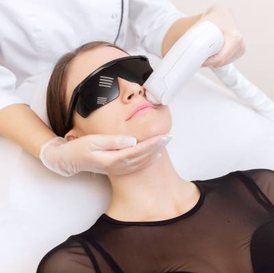 Junge Frau, bei einer Lichttherapie-Behandlung gegen Hautveränderungen mit einem BBL Laser.