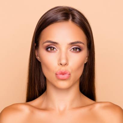Junge, dunkelhaarige Frau, mit schönen vollen Lippen nach einer Lippenunterspritzung.